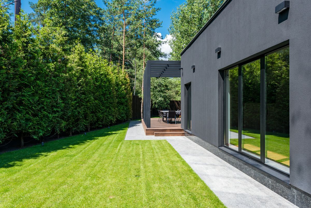 Modern backyard patio with striped lawn and pergola